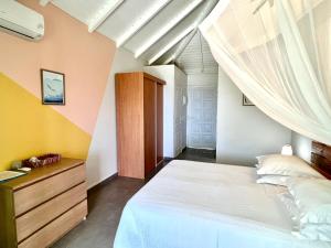 1 dormitorio con 1 cama blanca grande con cortinas en Cannelle en Deshaies