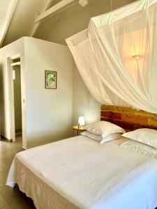 1 dormitorio con cama blanca y mosquitera en Cannelle en Deshaies