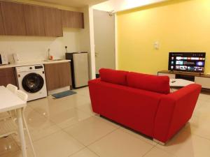 ein Wohnzimmer mit einem roten Sofa und einer Küche in der Unterkunft HB1613- 2 bedroom-Apartment -Wifi -Netflix-Parking, 3040 in Cyberjaya