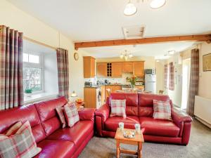 a living room with a red leather couch and a table at Hafod in Llanengan