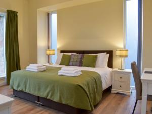 a bedroom with a large bed with towels on it at Falcon Cottage in Linlithgow