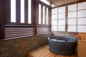 uma grande banheira num quarto com janelas em Onyado Shikishima-kan em Kotohira