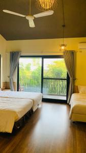 een slaapkamer met 2 bedden en een groot raam bij Khu nghỉ dưỡng Làng An Bình in Yên Bình