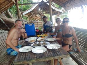 eine Gruppe von Menschen, die an einem Picknicktisch mit Essen sitzen in der Unterkunft Ferranco Tourist Inn in San Vicente