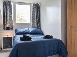 a bedroom with a blue bed and a window at Ewe Cottage in Ashbourne