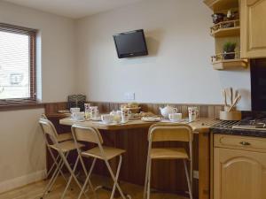 a kitchen with a table with chairs and a tv on the wall at Craigrossie Cottage in Auchterarder