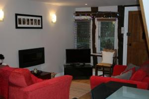 a living room with red chairs and a flat screen tv at Peel Cottage, Dilwyn in Dilwyn