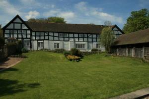 a large black and white building with a yard at Peel Cottage, Dilwyn in Dilwyn