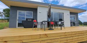 a house with a deck with chairs and an umbrella at Country Comfort in Hamilton