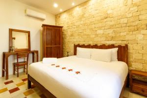 a bedroom with a large white bed and a brick wall at Hotel Boutique Casa Hipil in Valladolid