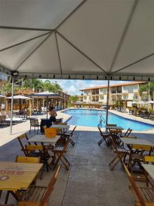 un grupo de mesas y sillas con piscina en Ondas Praia Resort, en Porto Seguro