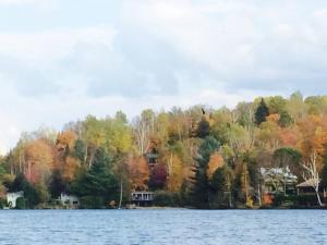 ein Haus am Ufer eines Sees in der Unterkunft Cozy Lake Loj + Hot Tub & Fire Pit in Huberdeau