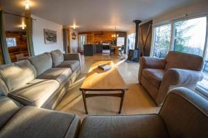 ein Wohnzimmer mit Sofas und einem Couchtisch in der Unterkunft Cozy Lake Loj + Hot Tub & Fire Pit in Huberdeau