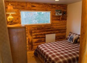 ein Schlafzimmer mit einem Bett in einer Blockhütte in der Unterkunft Cozy Lake Loj + Hot Tub & Fire Pit in Huberdeau