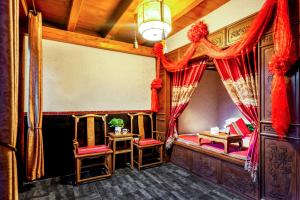 een kamer met rode gordijnen en 2 tafels en stoelen bij Pingyao Baichanghong Inn in Pingyao