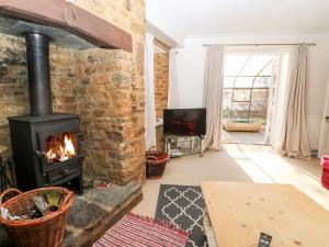 a living room with a brick wall and a wood stove at Stone Wheel Cottage in Hook Norton