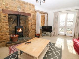 een woonkamer met een houten tafel en een open haard bij Stone Wheel Cottage in Hook Norton