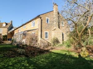 an old brick house with a grass yard in front of it at Stone Wheel Cottage in Hook Norton