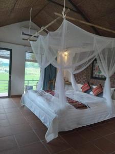 a bedroom with a white bed with a mosquito net at Mai Chau Green house in Mai Châu