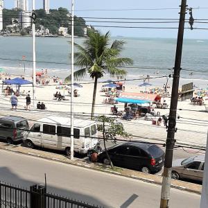 uma praia com carros estacionados na areia e pessoas em Apartamento pé na areia Praia do Gonzaguinha. em São Vicente