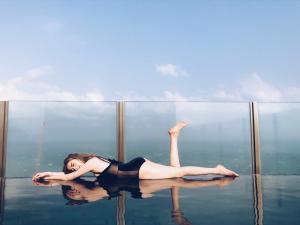 Una mujer tumbada de espaldas en el agua en 芭提雅双人精品公寓无边游泳池THEBASE中央基地, en Pattaya central
