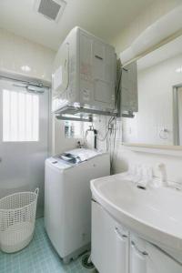a white kitchen with a sink and a refrigerator at 北谷宮城海岸まで徒歩1分/BBQ可能/最大12名/施設周辺おしゃれなカフェや飲食店多数 サンセットブリーズ北谷 in Hamakawa