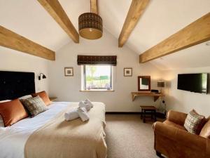 een slaapkamer met een bed, een bank en een tv bij Stylish & cosy barn minutes from the Lake District in Penrith