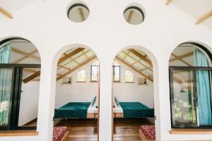 a bedroom in a house with windows and green sheets at Hygge Siargao in General Luna