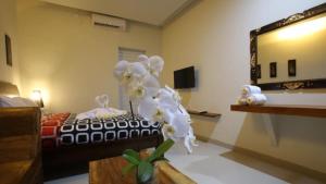 Habitación con cama, espejo y flor en Rai House Sanur, en Sanur