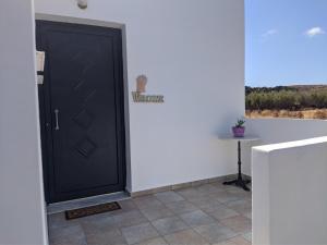 a black door in a white room with a table at Chrysiis House 2 in Analipsi