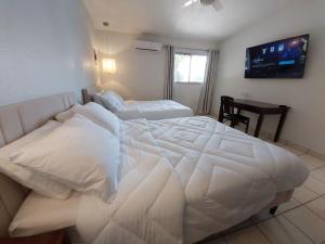 a bedroom with a large white bed and a desk at Point City Hotel in Guasave