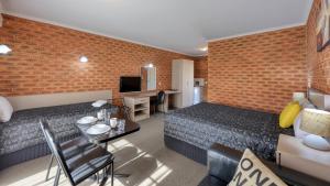 Habitación de hotel con 2 camas y comedor en Glider City Motel Benalla en Benalla