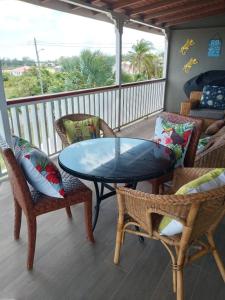 a porch with a glass table and chairs on a balcony at Fortescue Cherry Blossom Apartments in Saint Philip