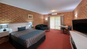 Glider City Motel Benalla في بينالا: غرفة فندق بسرير وجدار من الطوب