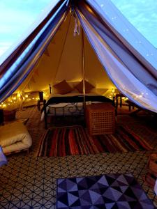 a tent with a bed in it with lights at Luxury 5m bell tent with log burner near Whitby in Saltburn-by-the-Sea