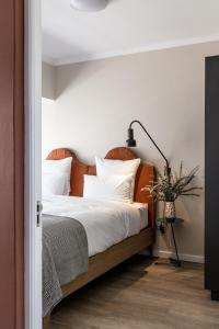 a bedroom with a bed with white sheets and a lamp at CURIOCITY Green Point in Cape Town