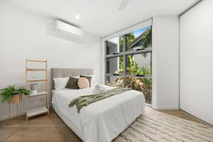a white bedroom with a bed and a large window at Luxury Alex Beach Home in Alexandra Headland