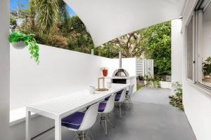 a white kitchen with a white table and chairs at Luxury Alex Beach Home in Alexandra Headland