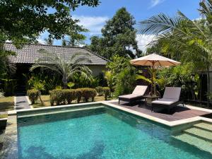 a swimming pool with two chairs and an umbrella at Kaien Villas Gili Air in Gili Air
