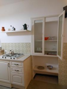 cocina con armarios blancos y fogones en B&B Le Stanze del Chiostro en Serra deʼ Conti