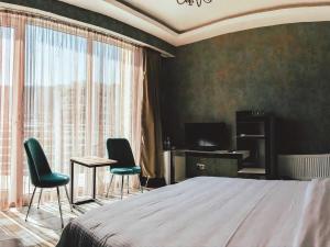 1 Schlafzimmer mit einem Bett, 2 Stühlen und einem Schreibtisch in der Unterkunft Panorama 360° Hotel in Tbilisi City