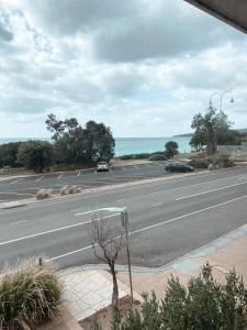 a road with cars parked in a parking lot next to the ocean at Stella's Dromana Hotel in Dromana