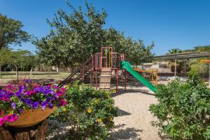 a playground with a slide in a park with flowers at Eilot Kibbutz Country Lodging in Eilat