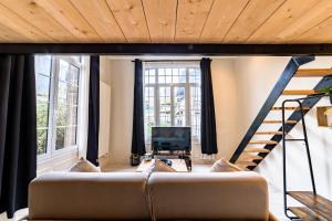 ein Wohnzimmer mit einem Sofa und einer Treppe in der Unterkunft Le Château Senard, Studio cosy 23 m2 au calme proche gare - 3 min in Rouen