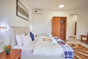 1 dormitorio con cama blanca y armario de madera en Malika Nungwi Hotel, en Nungwi