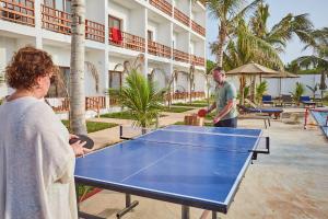 a man and a woman standing around a ping pong table at Malika Nungwi Hotel in Nungwi