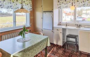 a kitchen with a table and a refrigerator at Nice Home In Bullaren With Wifi And 3 Bedrooms in Bullaren