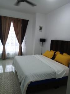Un dormitorio con una cama con almohadas amarillas y una ventana en Madinatus Syifa Homestay, en Kota Tinggi