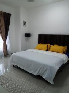 a bedroom with a large white bed with yellow pillows at Madinatus Syifa Homestay in Kota Tinggi