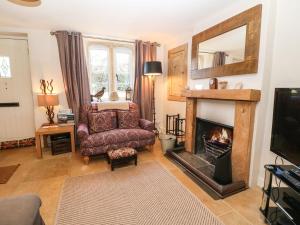 a living room with a chair and a fireplace at Green Pump Cottage in Blockley